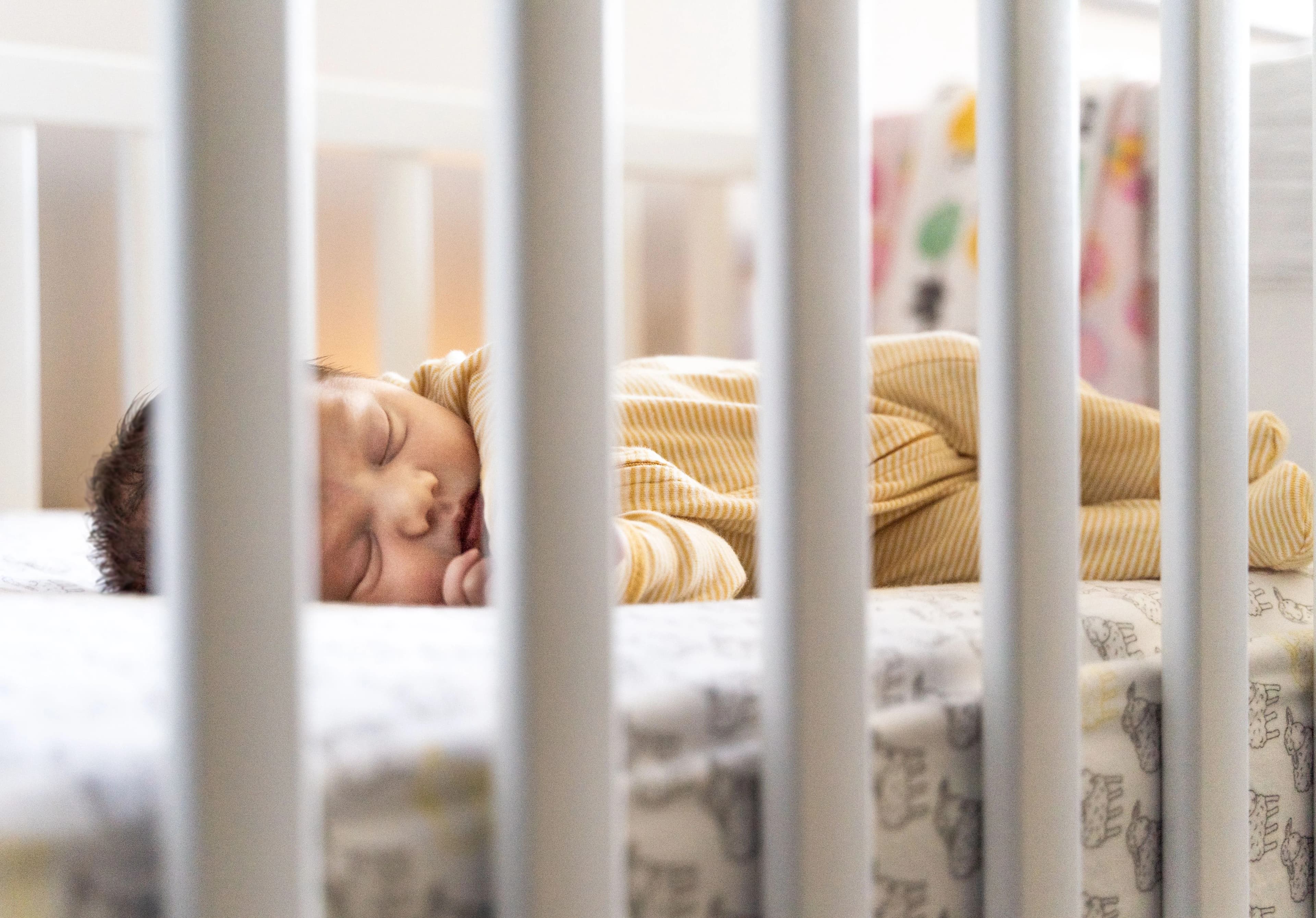 Father gently placing his baby into a wooden nursery cot — BabyCosts Australia