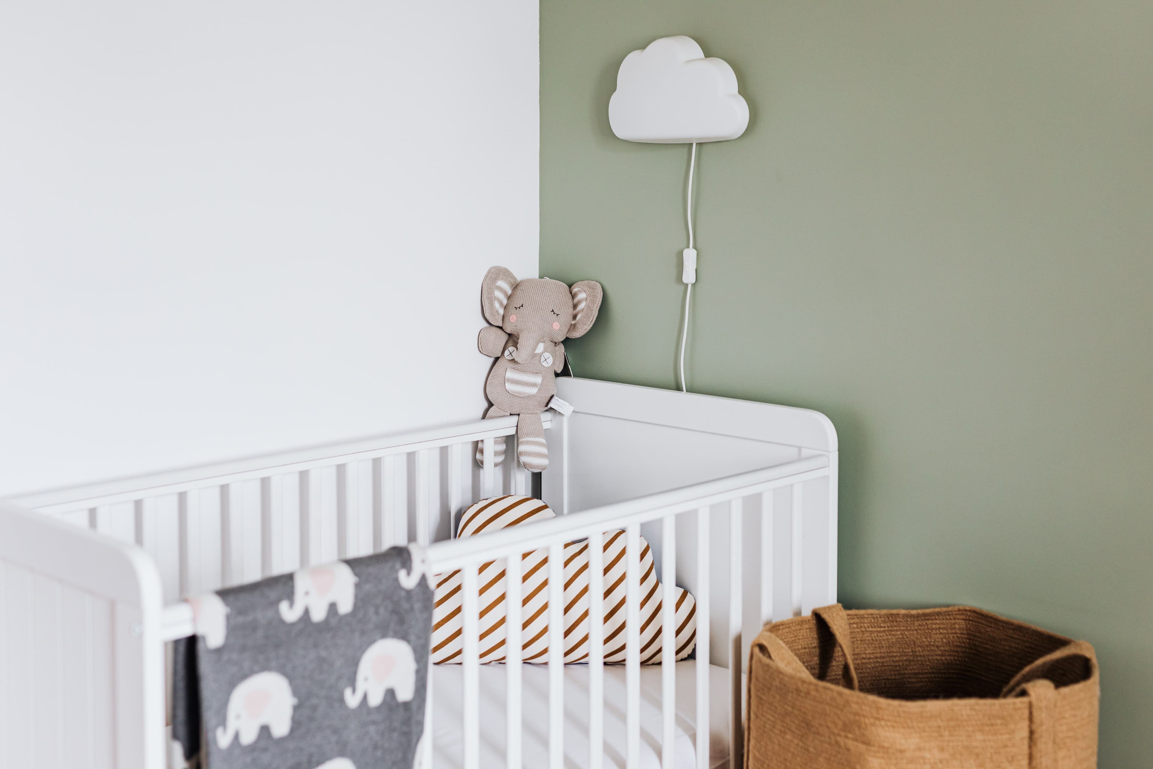 Father gently placing his baby into a wooden nursery crib — BabyCosts Australia