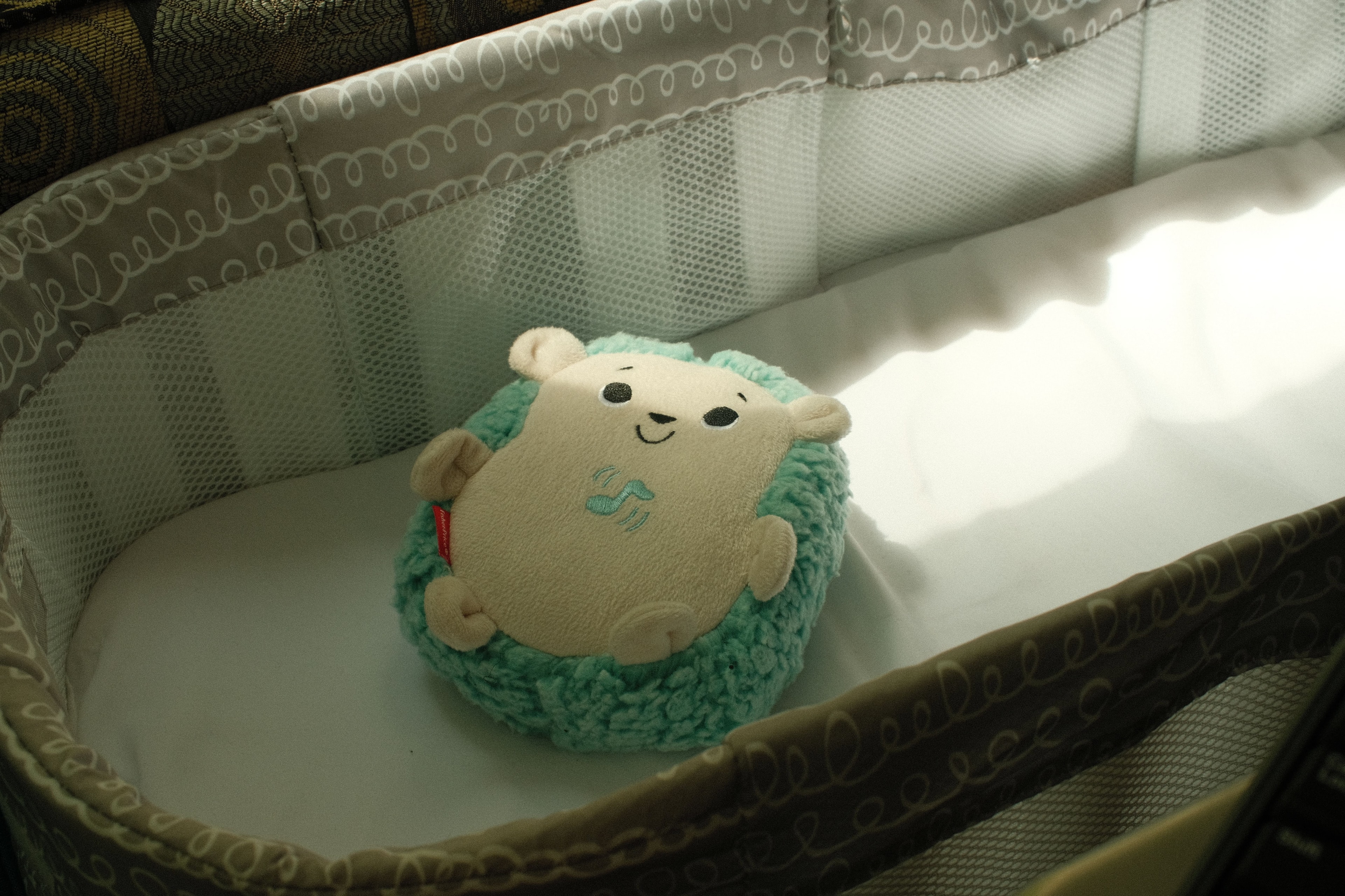 Soft plush teddy bear hanging from a baby nursery mobile