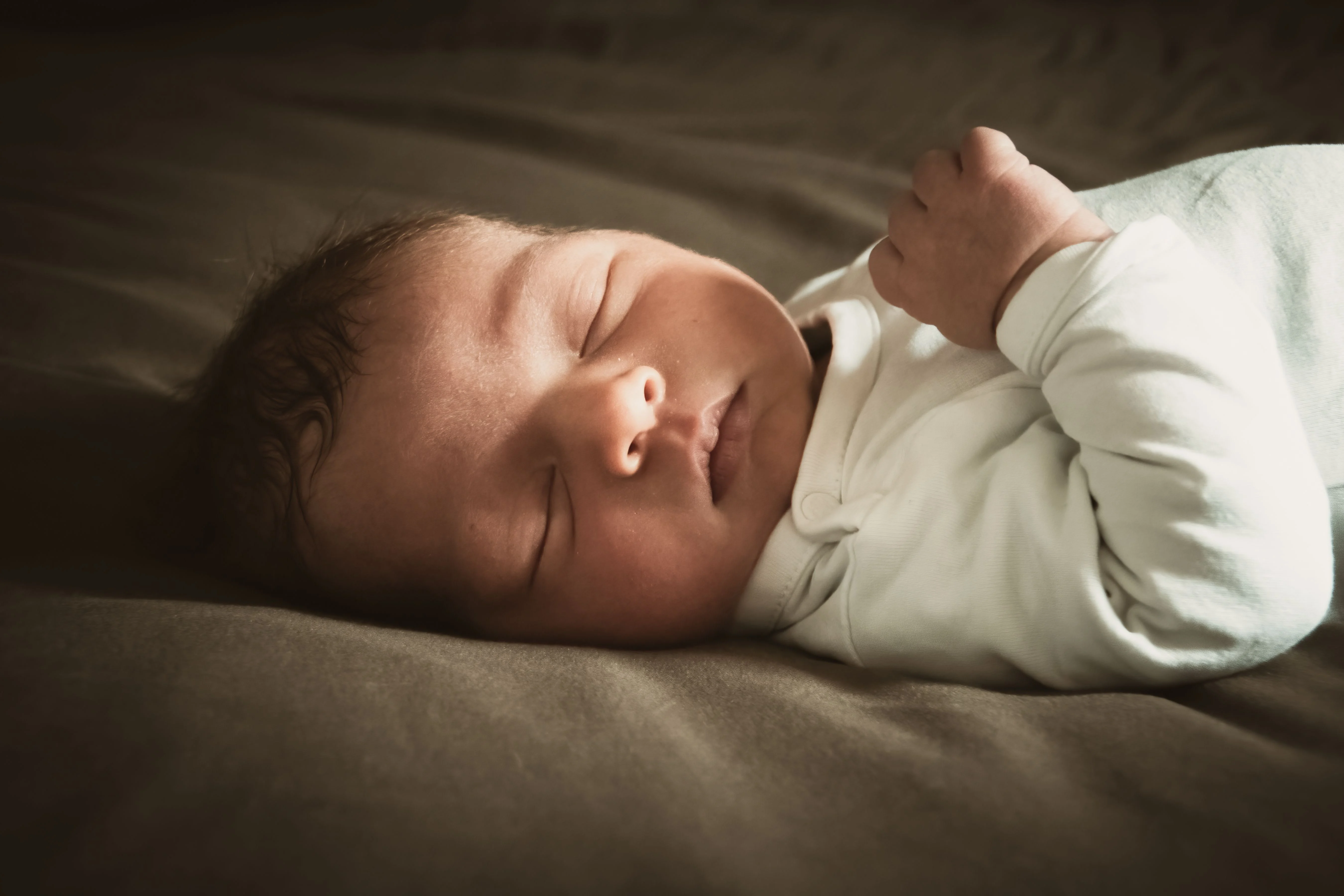 Father gently placing his baby into a wooden nursery cot