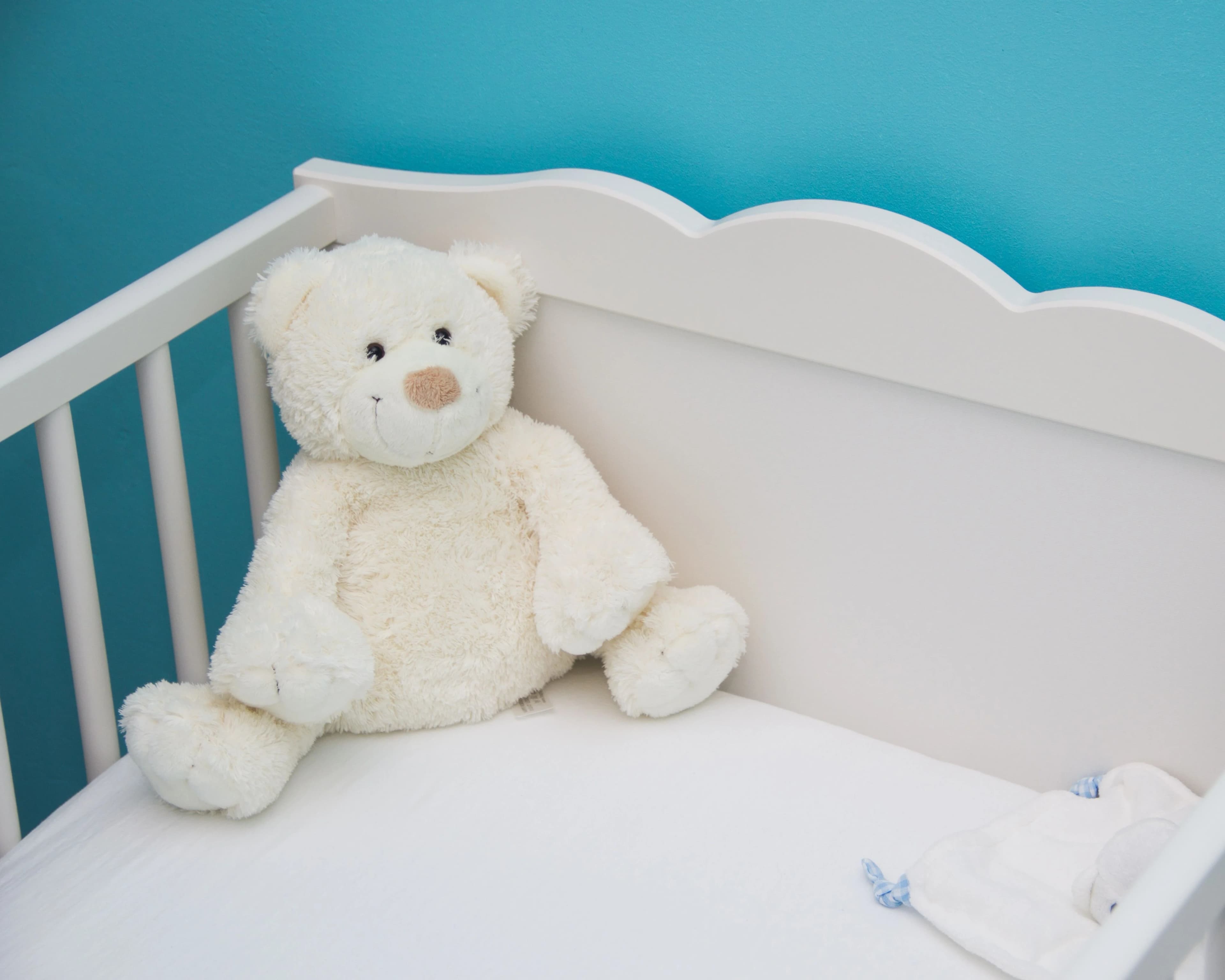 Soft plush teddy bear hanging from a baby nursery mobile — BabyCosts Australia