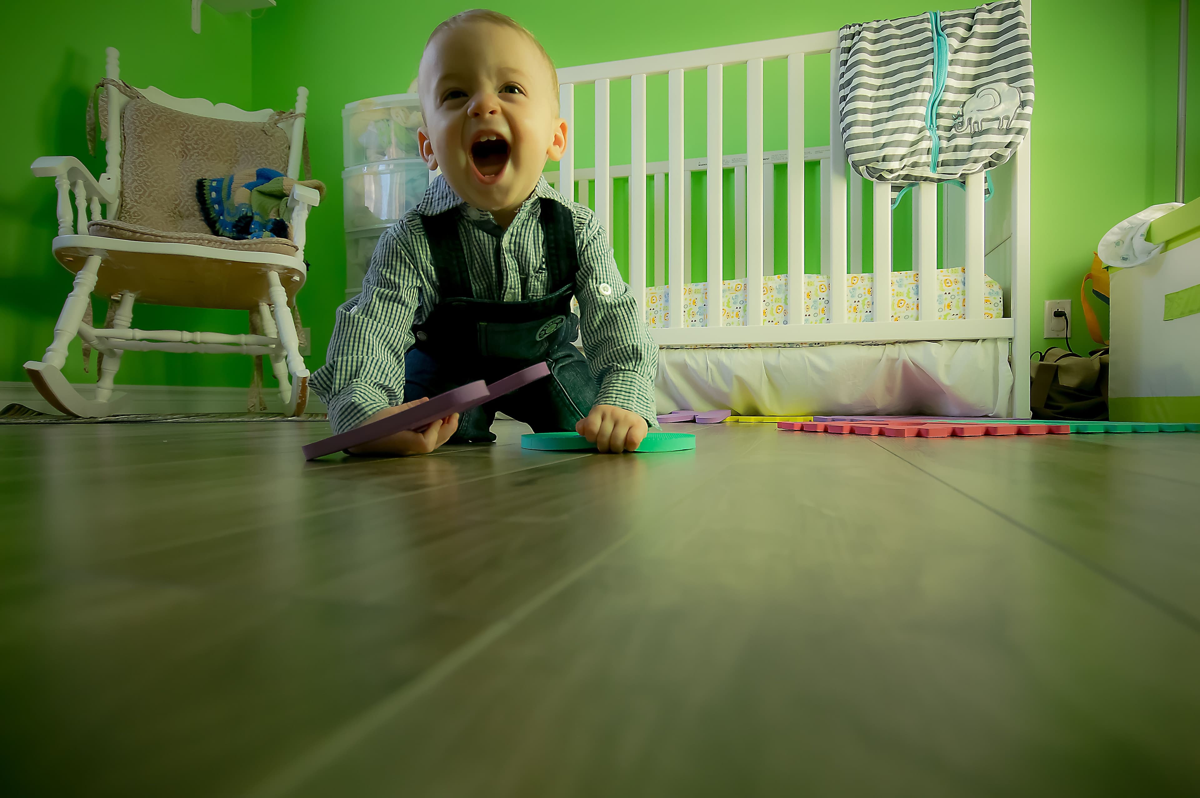 Father gently placing his baby into a wooden nursery crib — BabyCosts Australia
