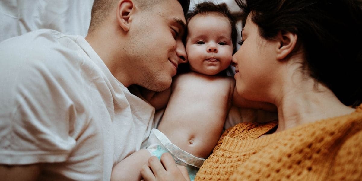 New parents bonding with their newborn baby in bed
